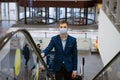 Young man wearing a mask climbs the escalator in the mall Royalty Free Stock Photo