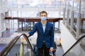 Young man wearing a mask climbs the escalator in the mall Royalty Free Stock Photo