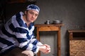 Young man wearing prison uniform sitting on a bed in a small prison cell Royalty Free Stock Photo