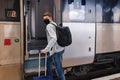 Young man wearing protective face mask standing near the train. Royalty Free Stock Photo