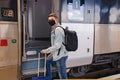 Young man wearing protective face mask standing on the railway station near the train. Royalty Free Stock Photo