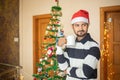 Young man wearing santa hat holding coffee mug in hand celebrating christmas alone at home, new year, holiday, party, winter, Royalty Free Stock Photo