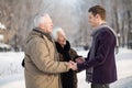 Young man wearing a scarf greets an elderly couple