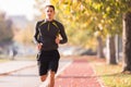 Young man wearing sportswear and running at quay during autumn Royalty Free Stock Photo