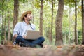 A young man wearing a straw hat happily uses a notebook while working in the forest garden.