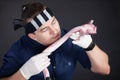 Young man wearing striped black and white bandanna sniffs long piece of raw meat, holding it in both hands in rubber gloves. Asian Royalty Free Stock Photo