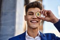 Young man wearing suit holding bitcoin over eye at street