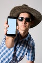 Young man wearing sunglasses and a hat in his hand phone shows Royalty Free Stock Photo