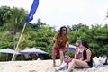 Young man wearing sunglasses takes selfie with young women sitting on the beach