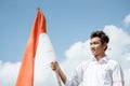 Young man wearing a white shirt and red and white attributes holding stick with Indonesian flag Royalty Free Stock Photo