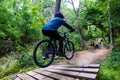 Young man wearing a white t-shirt and shorts performing a daring stunt while riding a mountain bike