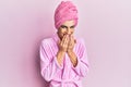 Young man wearing woman make up wearing shower towel on head and bathrobe laughing and embarrassed giggle covering mouth with