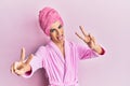 Young man wearing woman make up wearing shower towel on head and bathrobe smiling with tongue out showing fingers of both hands Royalty Free Stock Photo