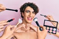Young man wearing woman make up with stylist all around him smiling in love doing heart symbol shape with hands Royalty Free Stock Photo