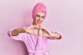 Young man wearing woman make up wearing shower towel on head and bathrobe smiling in love doing heart symbol shape with hands Royalty Free Stock Photo