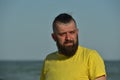 A young man wearing a yellow T-shirt and shorts. Man in a yellow T-shirt with a beard on the background of the sea Royalty Free Stock Photo