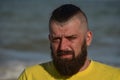 A young man wearing a yellow T-shirt and shorts. Man in a yellow T-shirt with a beard on the background of the sea Royalty Free Stock Photo