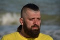 A young man wearing a yellow T-shirt and shorts. Man in a yellow T-shirt with a beard on the background of the sea Royalty Free Stock Photo