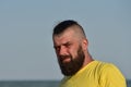 A young man wearing a yellow T-shirt and shorts. Man in a yellow T-shirt with a beard on the background of the sea Royalty Free Stock Photo