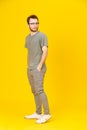 Young man wears eye glasses in casual wear posing on yellow background with hands in pockets looking sideways. Stylish Royalty Free Stock Photo