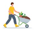 Young man with wheelbarrow with earth and plants.