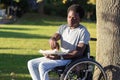 Young man in wheelchair enjoying his snack in park Royalty Free Stock Photo