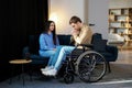 Young man in a wheelchair. Girlfriend comforting her sad boyfriend