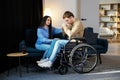 Young man in a wheelchair. Girlfriend comforting her sad boyfriend