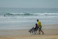 Young man in wheelchair and his frend on the road to the beach. Surf.