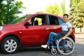 Young man in wheelchair opening door of car Royalty Free Stock Photo