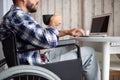 Young man in wheelchair working on laptop fromhome