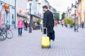 Young man wheeling a suitcase down a street Royalty Free Stock Photo