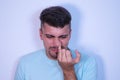 Young man on white background sticking his finger up his nose and pulling out a booger. The man is a pig. Concept various