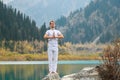 A young man in white clothes practices yoga in the mountains. Pose Samasthiti namaskar Royalty Free Stock Photo