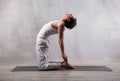 Young man in white clothes practicing yoga. Camel pose