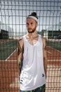 Young man with white headband on his head and tattoos on his arms dressed in the white t-shirt, black leggings and blue Royalty Free Stock Photo
