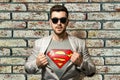 A young man in a white jacket and superman t-shirt, with a beard on a white background. horizontal frame