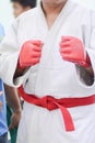 Young man in white kimono for sambo, judo, jujitsu posing on white background, looking straight, position of fighting post, hands Royalty Free Stock Photo