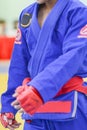 Young man in white kimono for sambo, judo, jujitsu posing on white background, looking straight, position of fighting post, hands