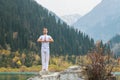 A young man in white practices yoga in the mountains. Pose Samasthiti namaskar Royalty Free Stock Photo