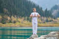 A young man in white practices yoga in the mountains. Pose Samasthiti namaskar Royalty Free Stock Photo