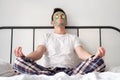 Young man in a white shirt with applied green cosmetic mask and pieces of cucumber Royalty Free Stock Photo