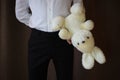 Young man in a white shirt and black pants holding a toy hare. A man with a big toy rabbit. a man in love. a gift for the woman I