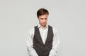 Young man in a white shirt and grey vest in high dudgeon over grey background Royalty Free Stock Photo