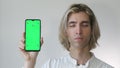 Young man in white shirt holding a smartphone, Green screen tamplate