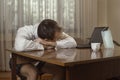 Young man in a white shirt with a tie and underwear was working at a computer at home tired and laid his head on the table. Royalty Free Stock Photo