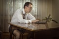 Young man in a white shirt with a tie and underwear works at a computer at home. Royalty Free Stock Photo