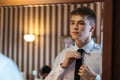 A young man ties up a tie in front of a mirror in room Royalty Free Stock Photo