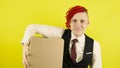 Young man in white shirt, vest and tie with cardboard box on yellow background in studio. Male courier with positive