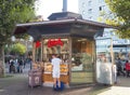 Young man with white training clothes stands in front of small glass bakery pavilion at bus stop